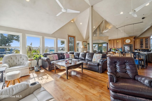 living room featuring high vaulted ceiling, ceiling fan, and light hardwood / wood-style flooring