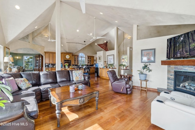 living room with wood-type flooring, high vaulted ceiling, and a fireplace