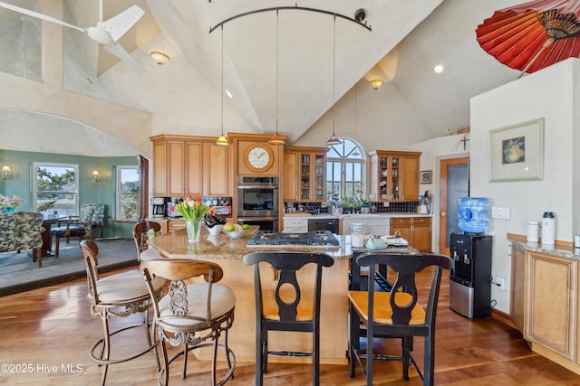 kitchen featuring dark hardwood / wood-style flooring, light stone counters, high vaulted ceiling, and stainless steel double oven