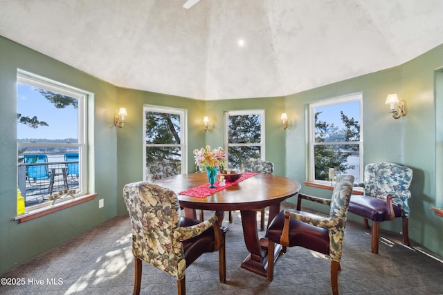 dining room featuring dark carpet and vaulted ceiling