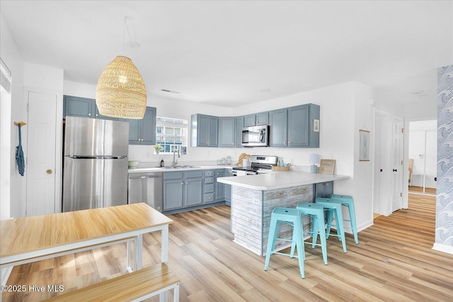 kitchen featuring a breakfast bar, stainless steel appliances, kitchen peninsula, and light hardwood / wood-style floors