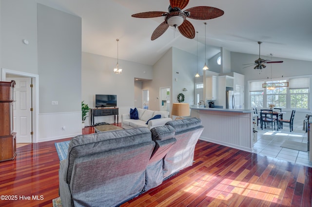 living room featuring ceiling fan with notable chandelier, dark hardwood / wood-style floors, and high vaulted ceiling