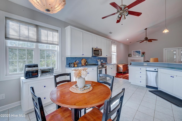 dining area featuring sink, vaulted ceiling, and light tile patterned floors