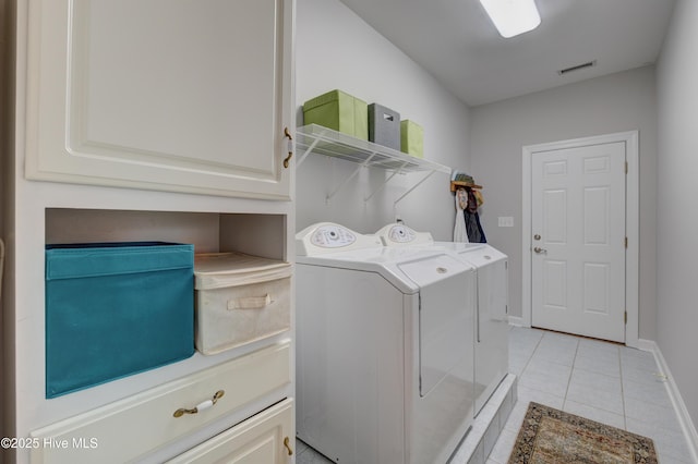 laundry area featuring light tile patterned floors, cabinets, and washer and dryer