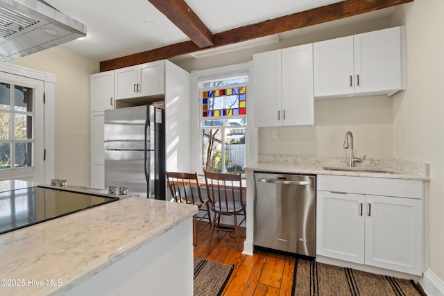 kitchen featuring sink, light hardwood / wood-style flooring, appliances with stainless steel finishes, white cabinets, and beamed ceiling