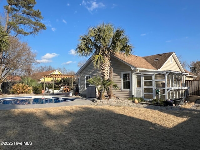 rear view of property with a fenced in pool, a sunroom, and a pergola