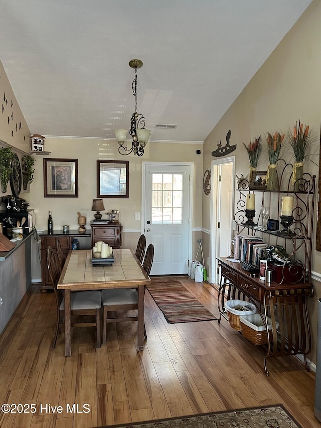 dining area featuring an inviting chandelier, lofted ceiling, and wood-type flooring