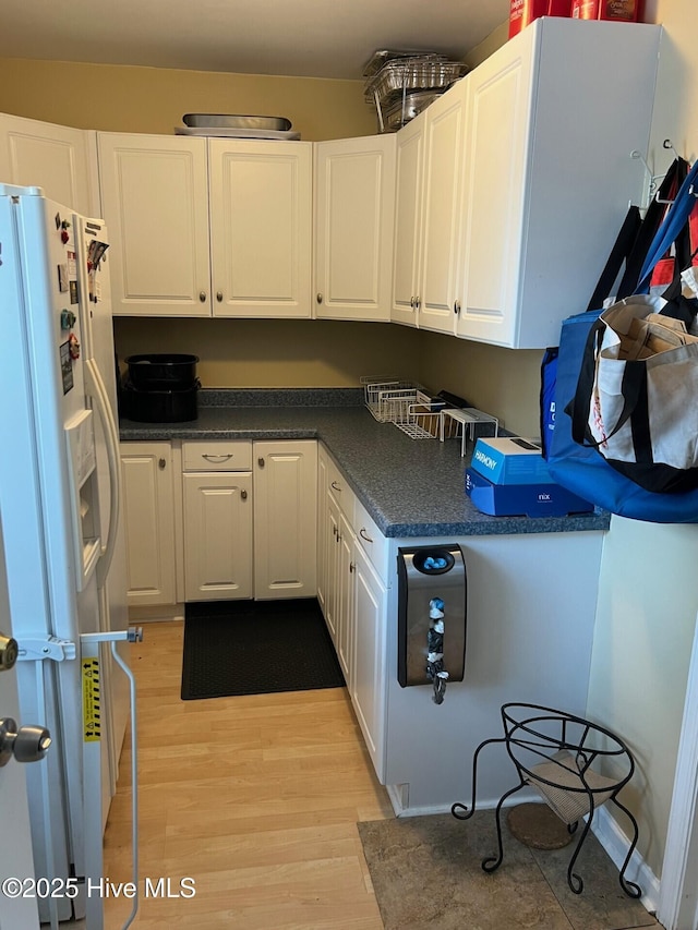 kitchen featuring white refrigerator with ice dispenser, white cabinets, and light wood-type flooring