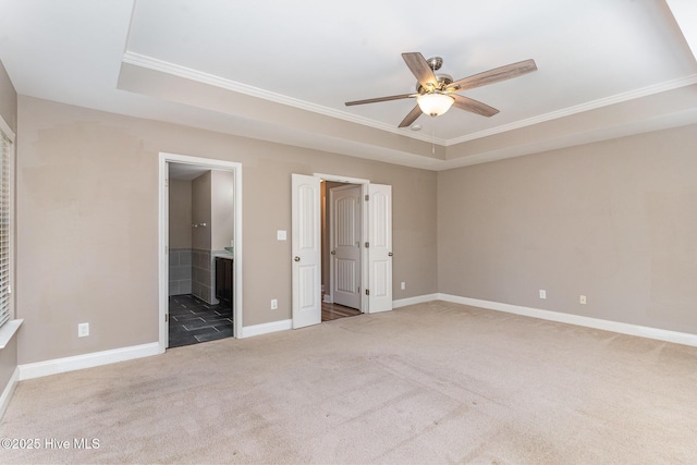 unfurnished bedroom featuring crown molding, ensuite bath, carpet floors, and a raised ceiling