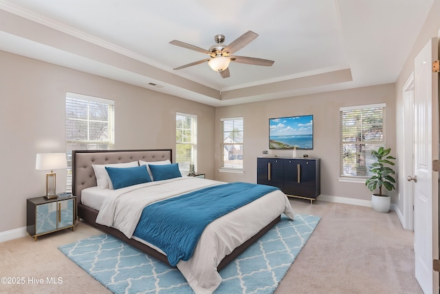 carpeted bedroom with ceiling fan, ornamental molding, a raised ceiling, and multiple windows