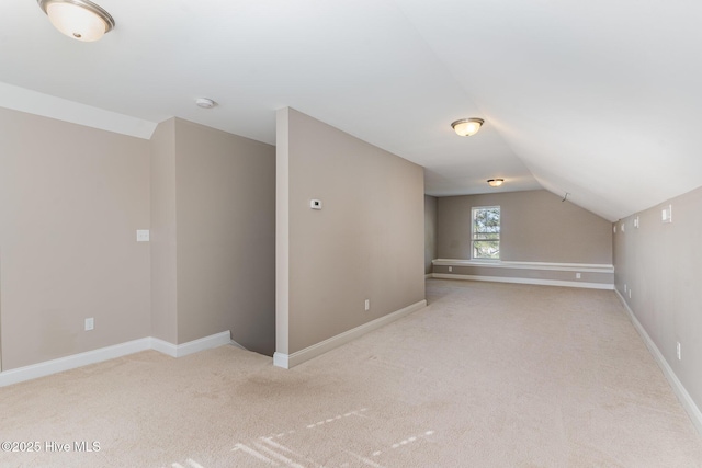 additional living space featuring lofted ceiling and light colored carpet