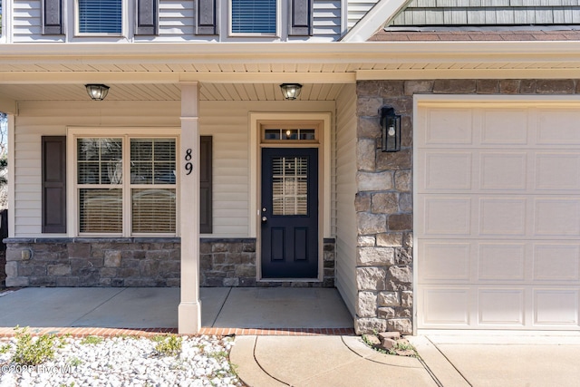 view of exterior entry featuring a porch and a garage