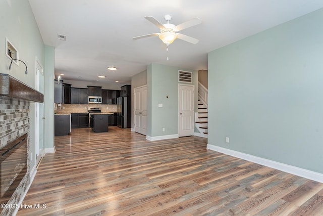 unfurnished living room with a brick fireplace, hardwood / wood-style flooring, and ceiling fan