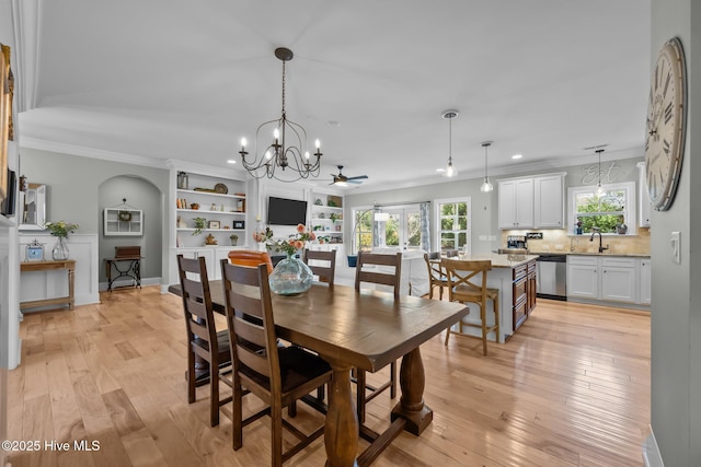 dining area with ceiling fan with notable chandelier, ornamental molding, light wood-style flooring, and baseboards