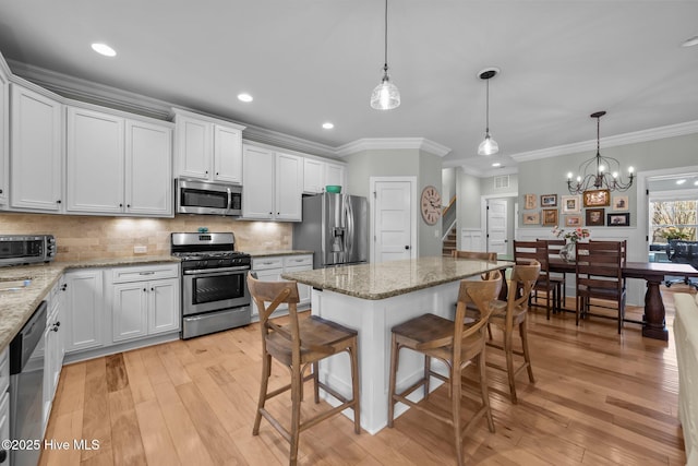 kitchen featuring a breakfast bar area, light wood-style flooring, stainless steel appliances, white cabinetry, and decorative backsplash