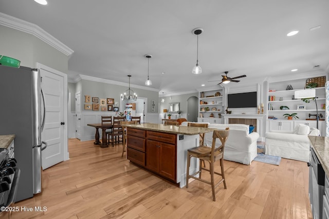 kitchen with freestanding refrigerator, a kitchen breakfast bar, crown molding, and light wood finished floors