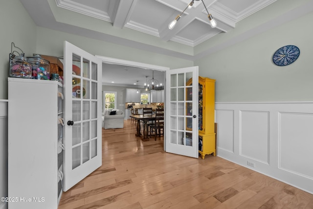 interior space with french doors, coffered ceiling, a notable chandelier, and wood finished floors