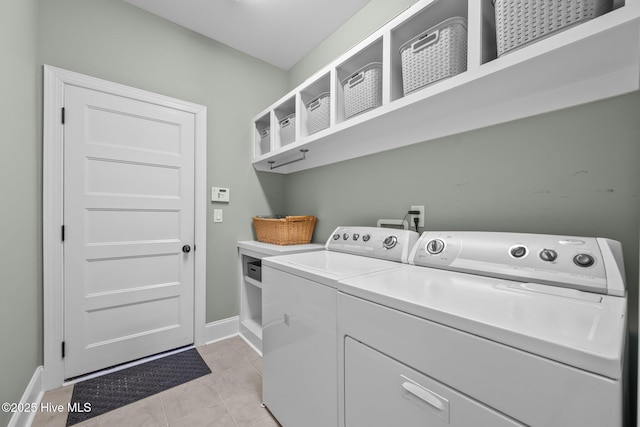 washroom featuring baseboards, laundry area, light tile patterned flooring, and washer and dryer