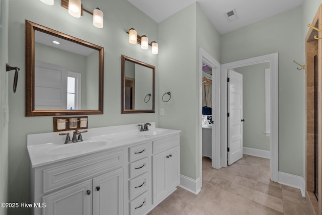 full bath with double vanity, a sink, visible vents, and baseboards