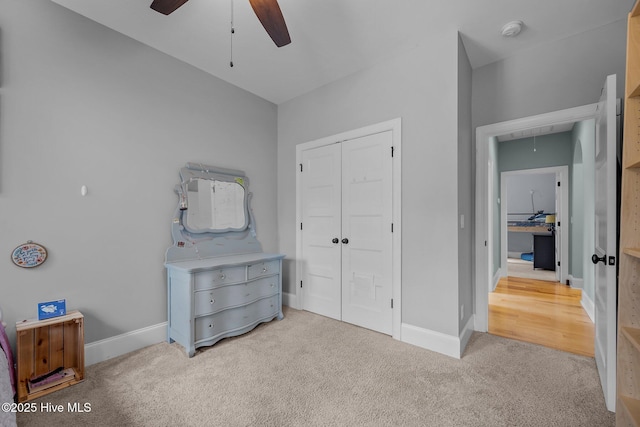 carpeted bedroom with attic access, a closet, baseboards, and a ceiling fan