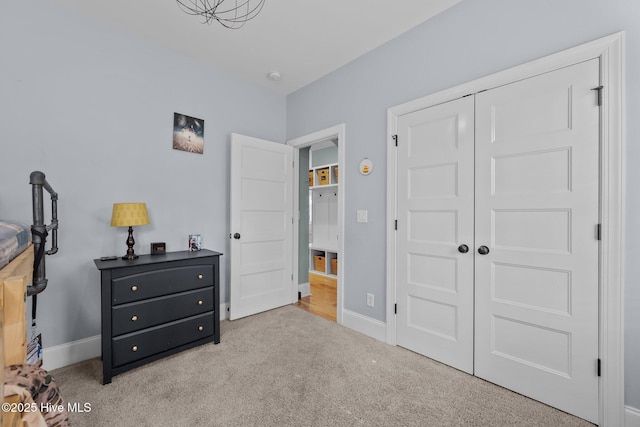 carpeted bedroom featuring a closet and baseboards