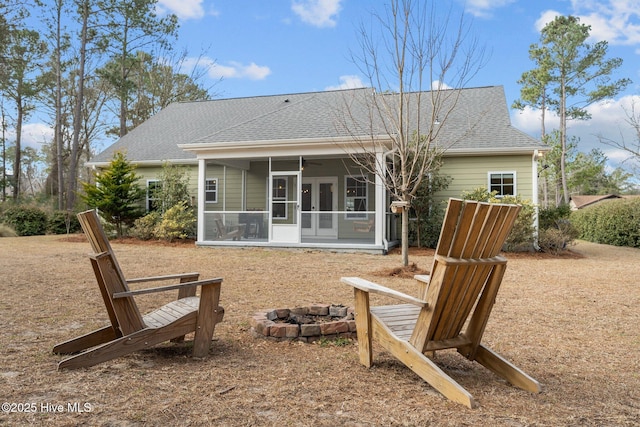 back of house with a sunroom, an outdoor fire pit, french doors, and roof with shingles