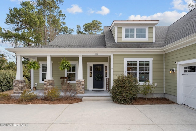 view of front of property with covered porch, roof with shingles, and a garage