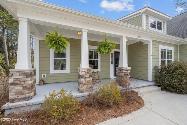 view of exterior entry featuring a porch and a shingled roof