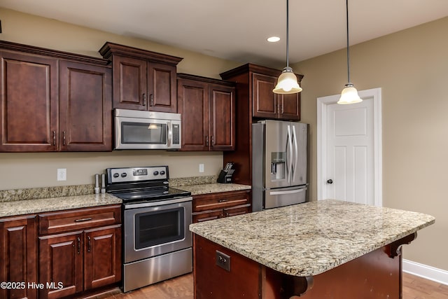 kitchen featuring stainless steel appliances, a kitchen island, a kitchen bar, and light hardwood / wood-style flooring