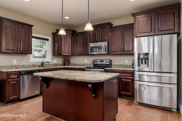 kitchen featuring a kitchen bar, decorative light fixtures, a kitchen island, and appliances with stainless steel finishes