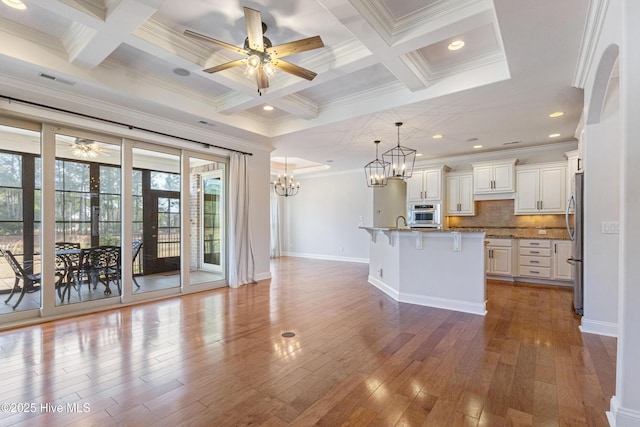 kitchen featuring a breakfast bar area, hanging light fixtures, stainless steel appliances, a kitchen island with sink, and white cabinets