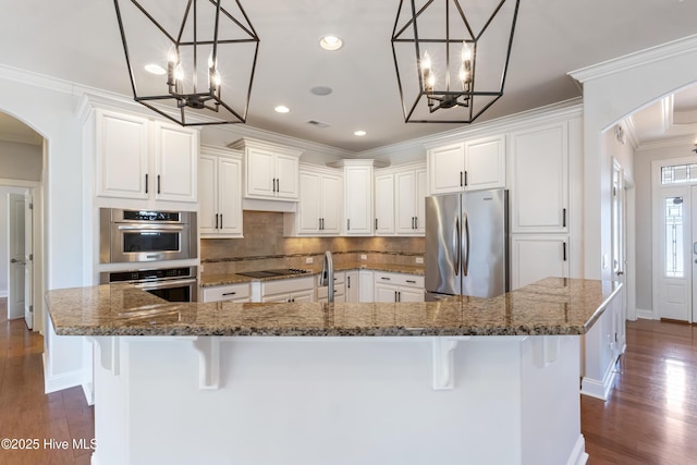 kitchen featuring a large island, stainless steel appliances, a kitchen bar, and dark stone counters