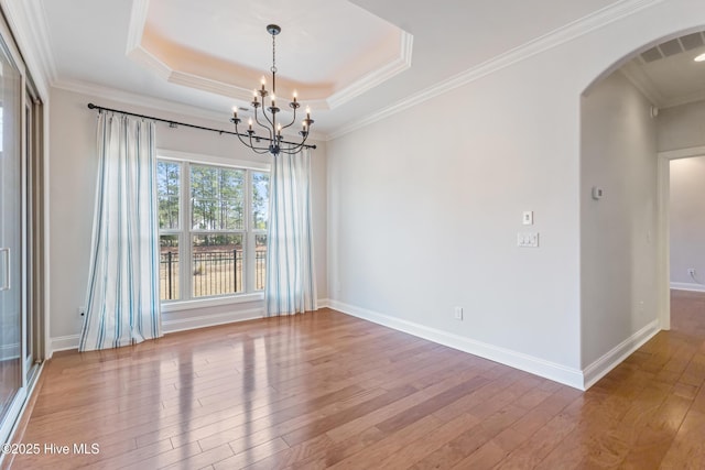 unfurnished room with hardwood / wood-style flooring, crown molding, a raised ceiling, and a chandelier