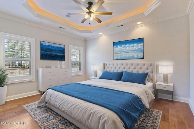 bedroom featuring ornamental molding, a raised ceiling, and light wood-type flooring