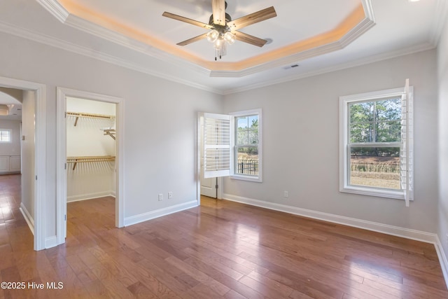 unfurnished bedroom featuring multiple windows, a raised ceiling, and dark wood-type flooring