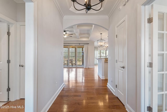 hall with coffered ceiling, a chandelier, ornamental molding, dark hardwood / wood-style flooring, and beam ceiling