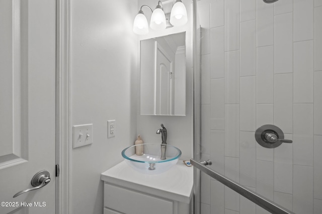 full bath featuring tiled shower and vanity