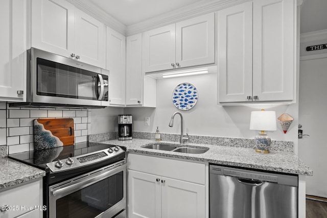 kitchen with white cabinets, appliances with stainless steel finishes, a sink, light stone countertops, and backsplash