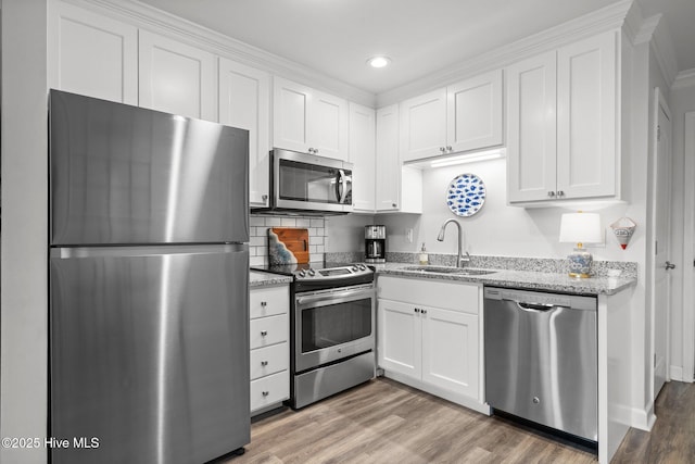 kitchen featuring stainless steel appliances, light wood-style floors, white cabinetry, and a sink