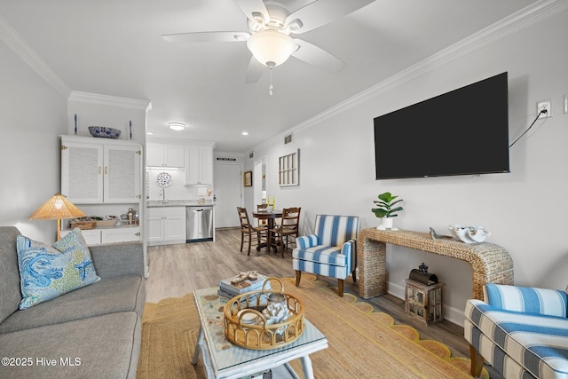 living area with ceiling fan, ornamental molding, visible vents, and light wood-style floors