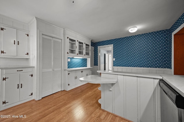 kitchen with white cabinetry, stainless steel dishwasher, kitchen peninsula, and light hardwood / wood-style flooring