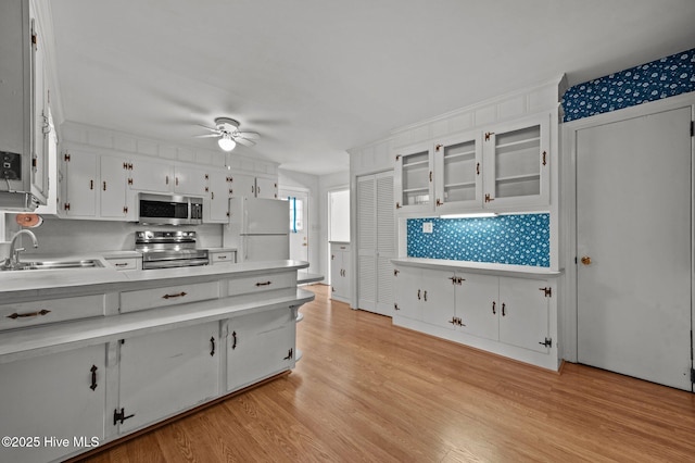 kitchen featuring appliances with stainless steel finishes, white cabinetry, sink, ceiling fan, and light wood-type flooring