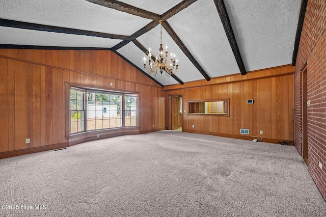 unfurnished living room featuring wooden walls, lofted ceiling with beams, light carpet, a textured ceiling, and an inviting chandelier