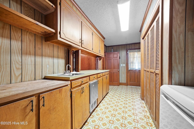 kitchen with sink, a textured ceiling, and wooden walls