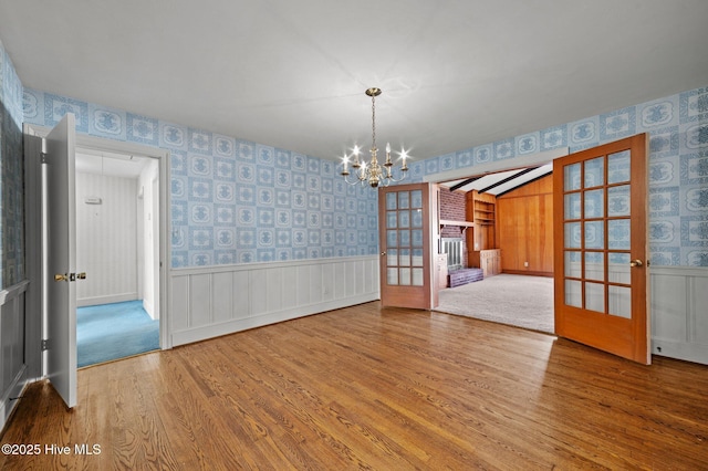 unfurnished dining area featuring hardwood / wood-style floors, a notable chandelier, and french doors