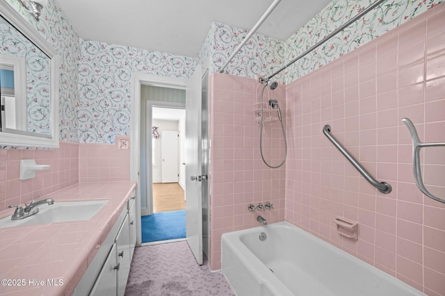 bathroom with vanity, tiled shower / bath combo, and tile walls