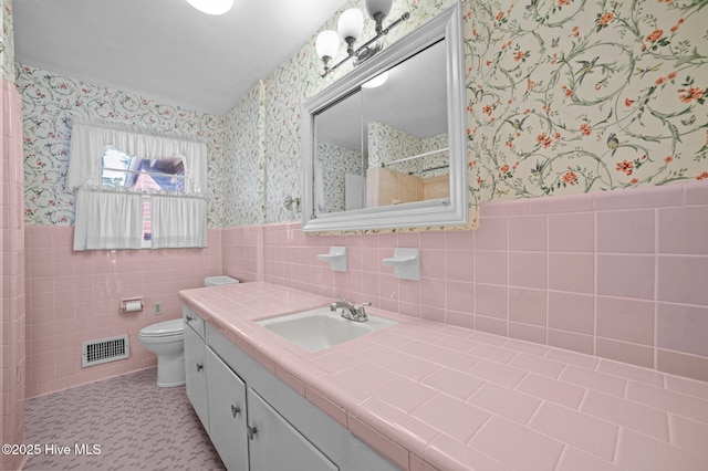 bathroom with tile patterned floors, toilet, vanity, and tile walls