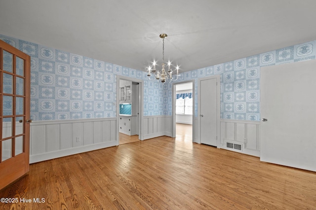 spare room featuring an inviting chandelier and light wood-type flooring