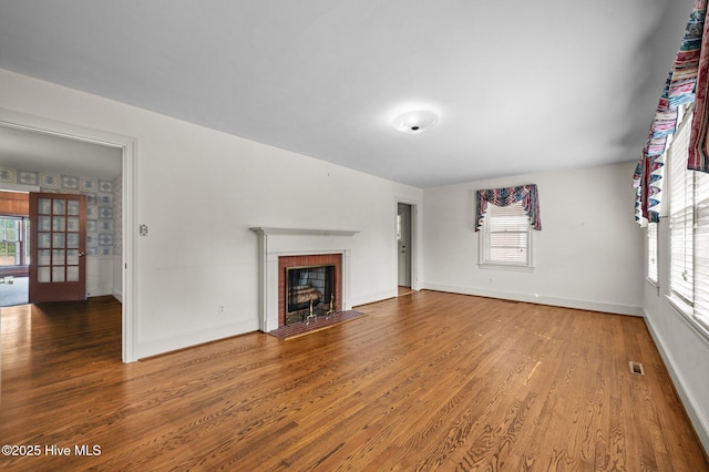 unfurnished living room with hardwood / wood-style floors and a brick fireplace