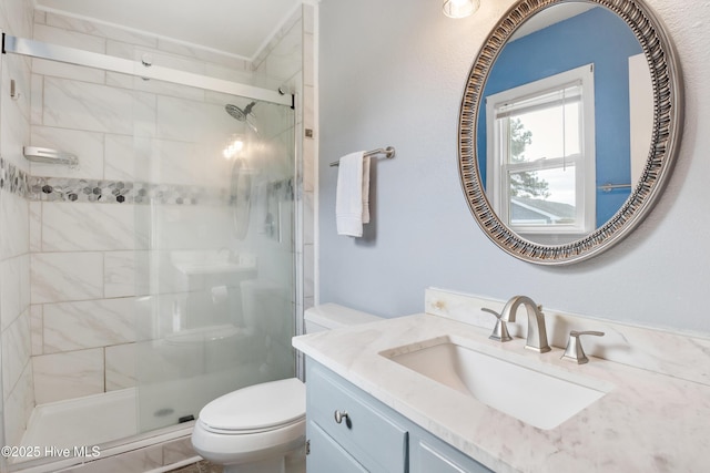 bathroom featuring a shower with door, vanity, and toilet